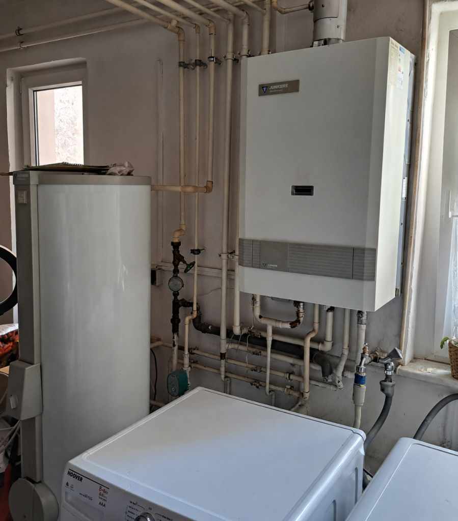 alte Gasheizung Alte Gasheizung mit Warmwasserspeicher und alten Rohren im Hauswirtschaftsraum HWR